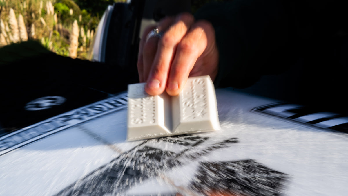 Rubbing a bar of Sticky Johnson wax across a surfboard deck