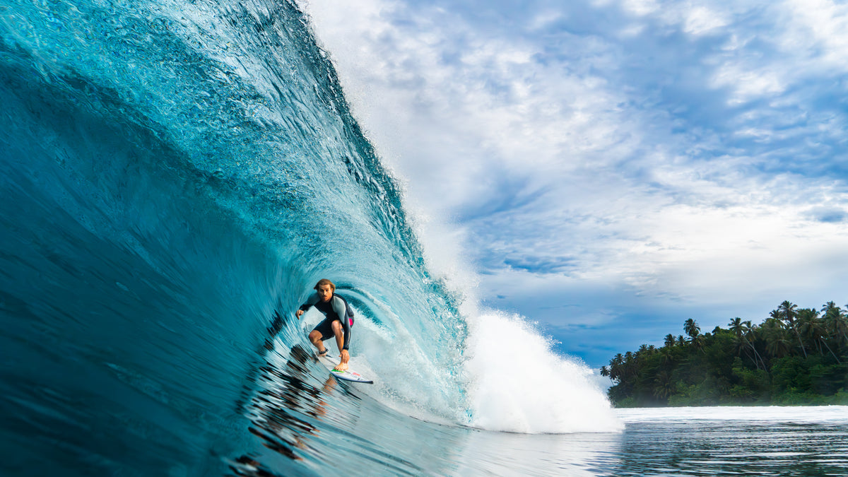 A surfer tucked inside a blue, glassy barrel