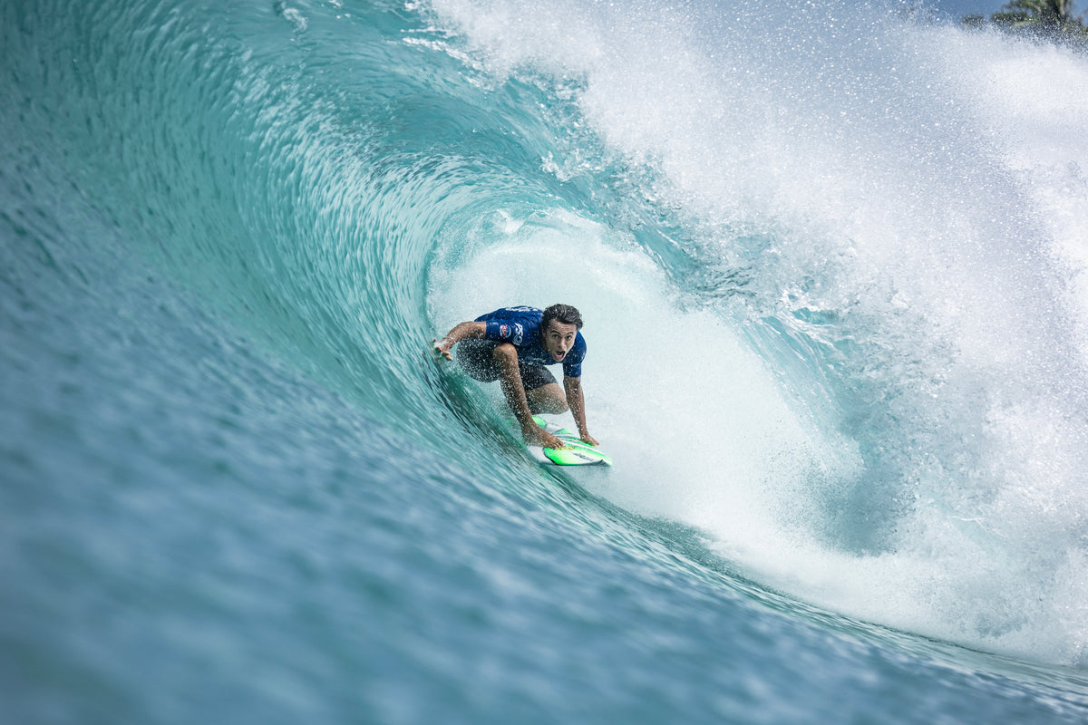 Surfer riding a wave in clear blue water